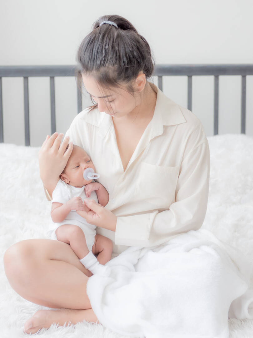 A beautiful Asian woman puts her newborn baby on her body