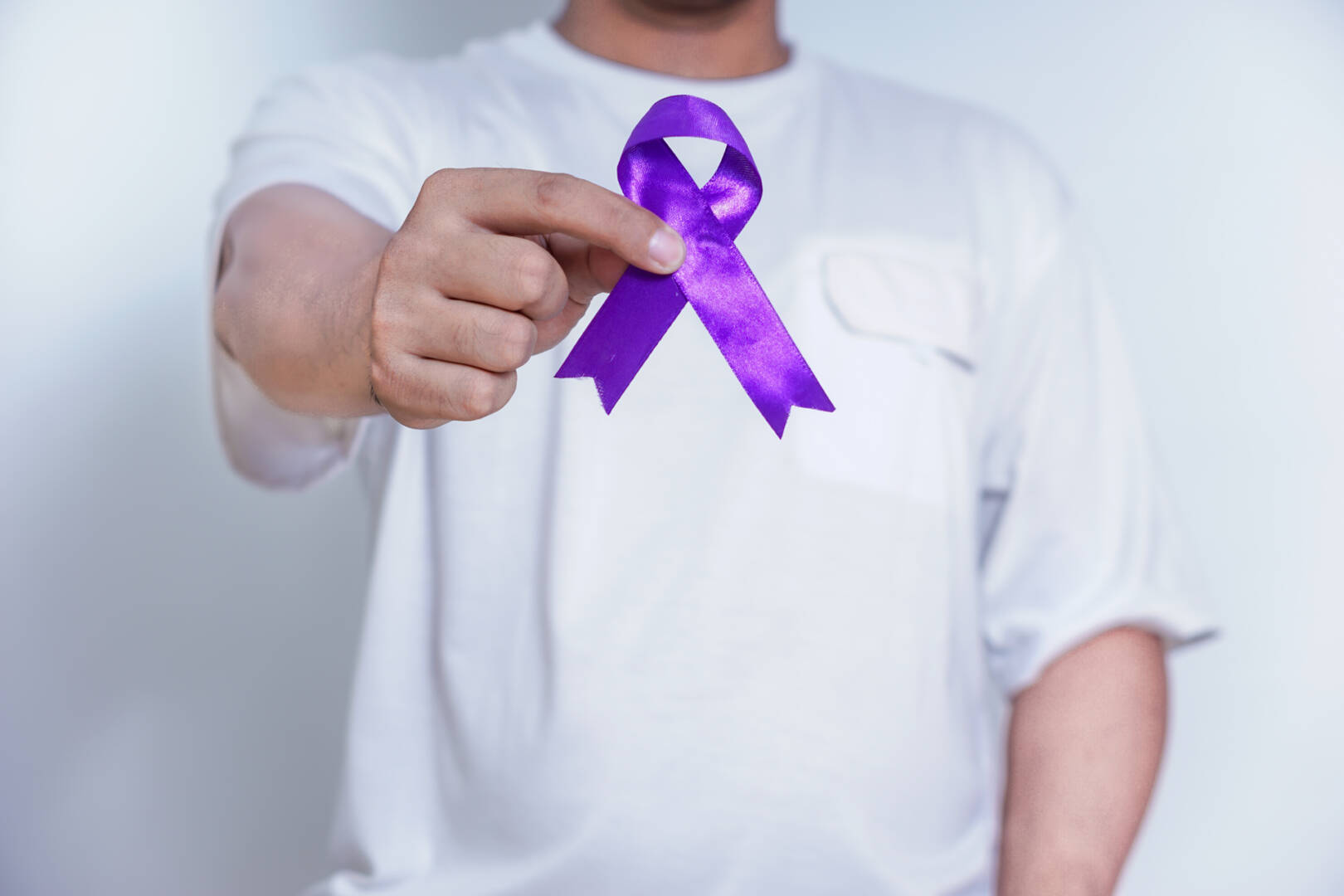 A person holding a purple ribbon, symbolizing awareness and support for various causes, including cancer. Healthcare and World cancer day concept
