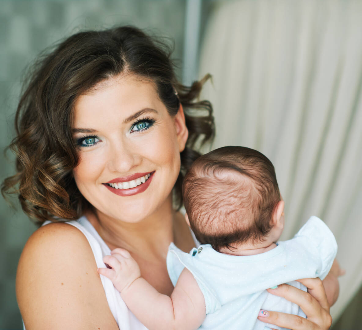 Close up portrait of beautiful young mother holding little baby