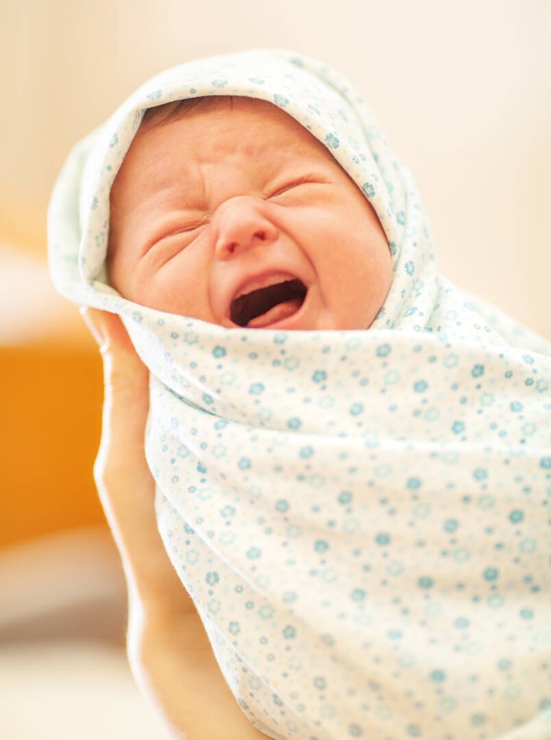 Crying newborn in mothers hands