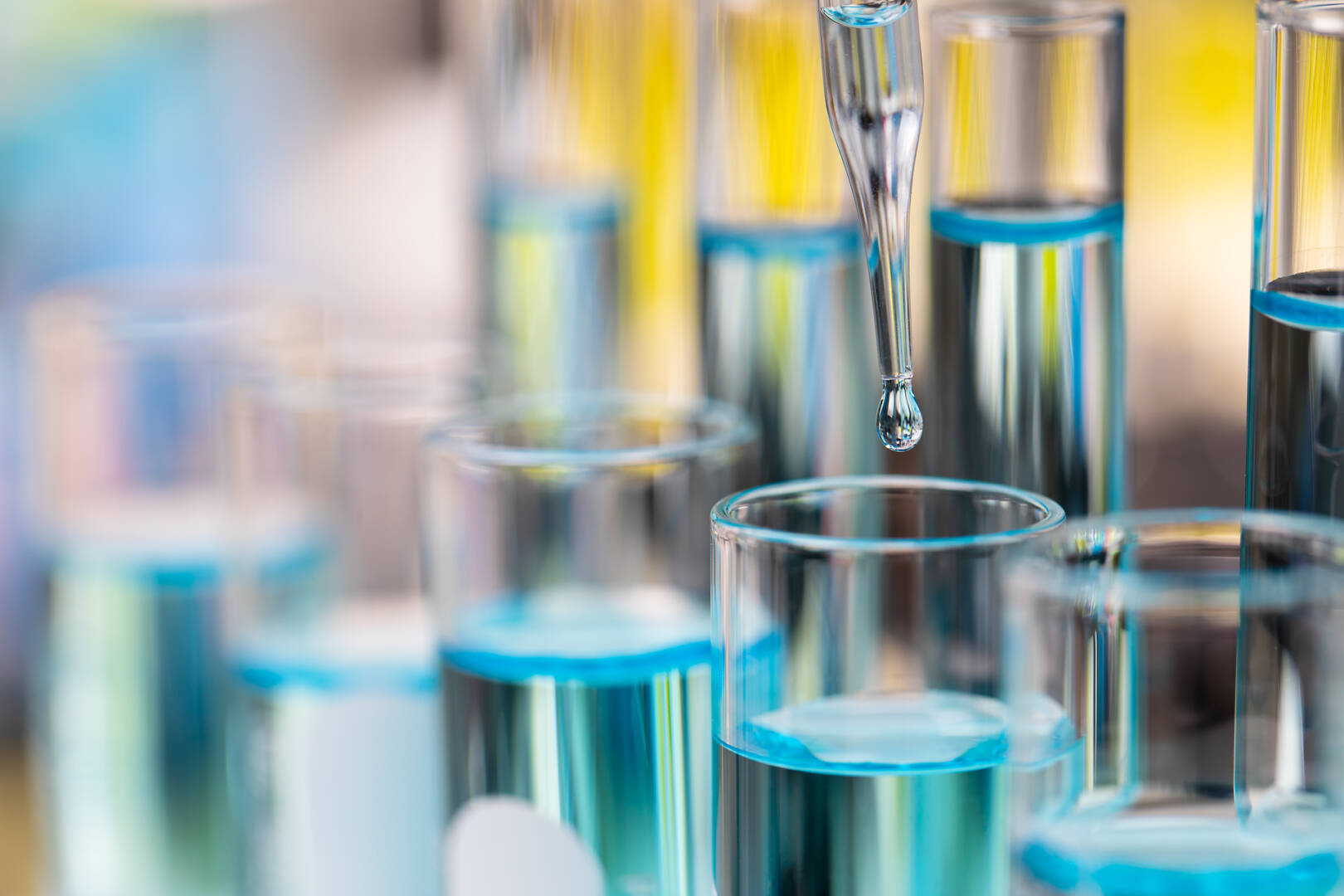 Drop of clear blue liquid from droper droping to test tube in la