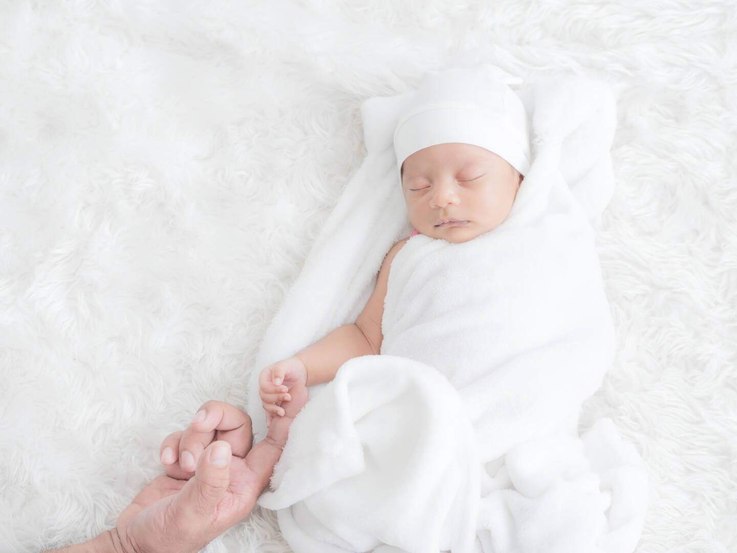 Newborn baby girl sleeps warmly on the white cloth and touched h