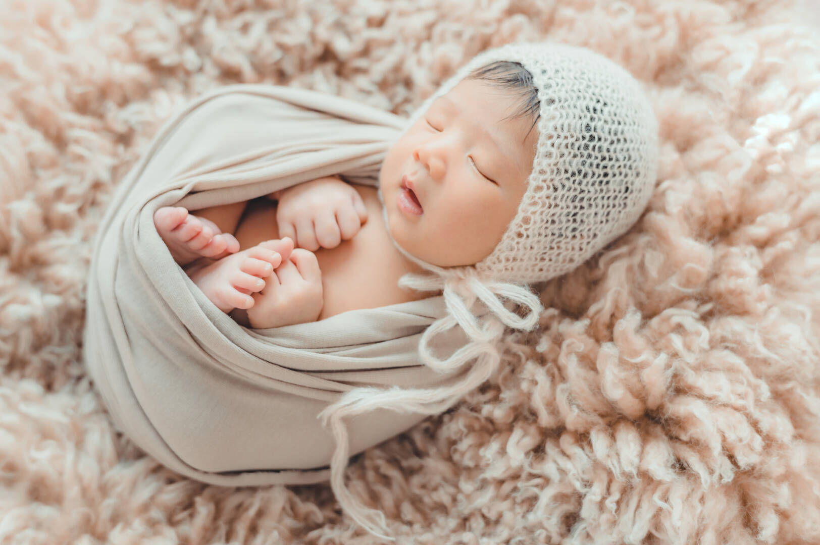 newborn baby wrapprd in cocoon sleeping on fur