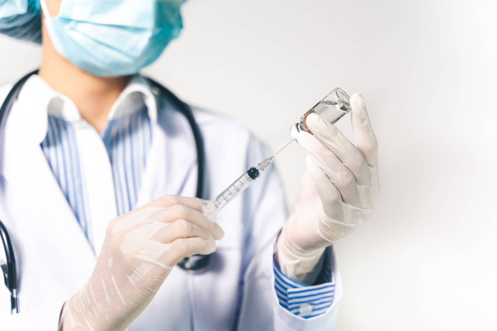 The doctor holding a syringe with Covid-19 vaccines in glass bot
