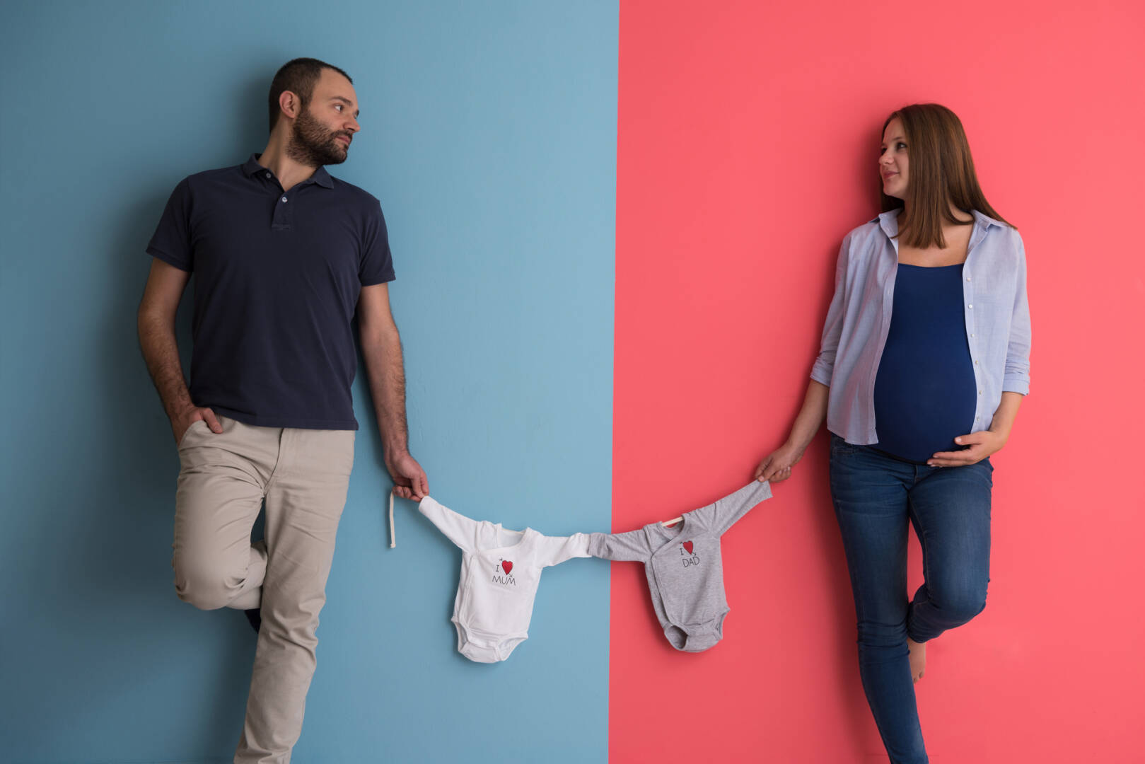 young couple holding baby bodysuits