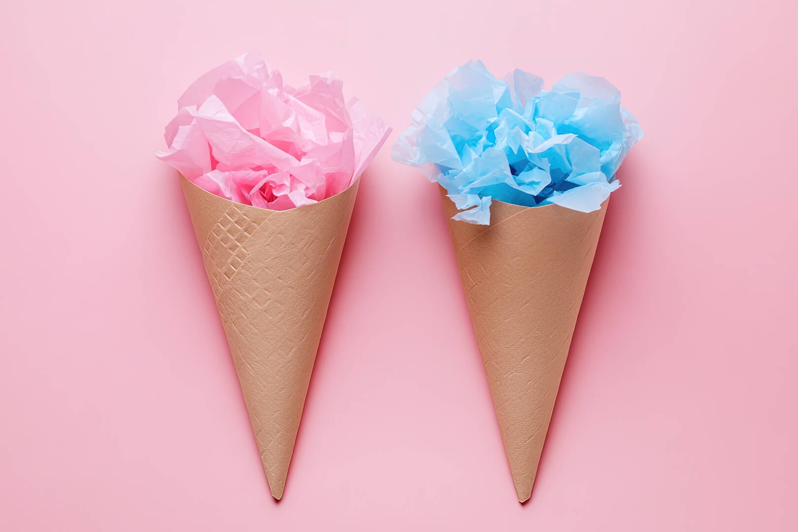 Pink and blue tissue paper fill waffle cones against a solid pink backdrop