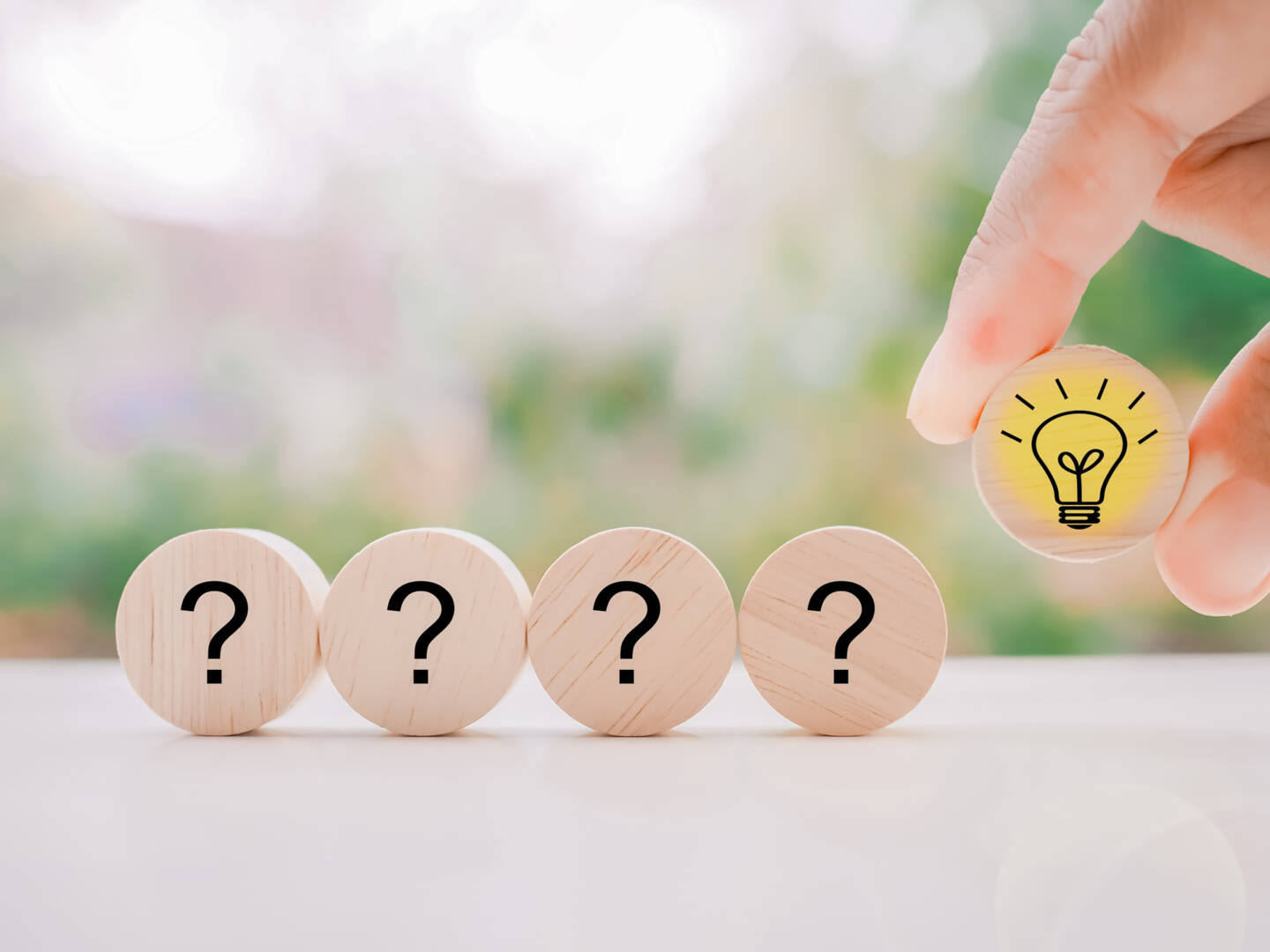 Close up hand arranging wooden block with light bulb and wooden block with question mark for leadership, creative, idea, innovation concept.