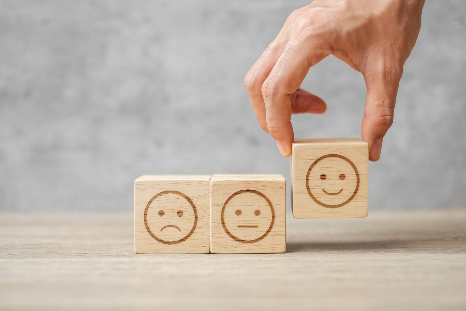 Man hand holding emotion face block. Customer choose Emoticon fo